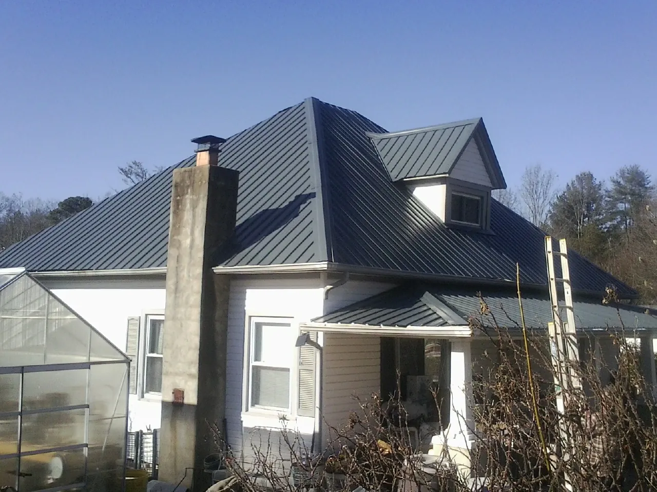 Dark blue standing seam metal roof on a white farmhouse with dormer — Slate & Tile Roof Repair by Roofing Brothers in Ruthton