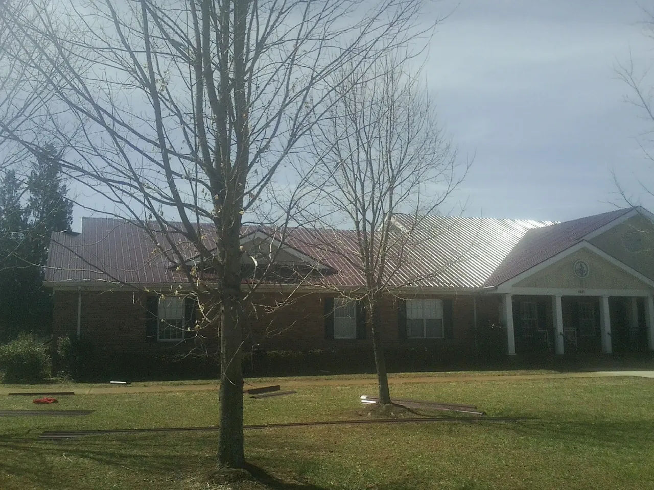 Red metal roof on a brick building seen from the front lawn in Ruthton