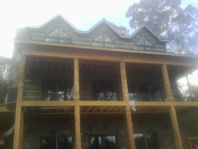 Dormers and porch framing on a large log home under construction — Roof Coating work by our crew in Ruthton
