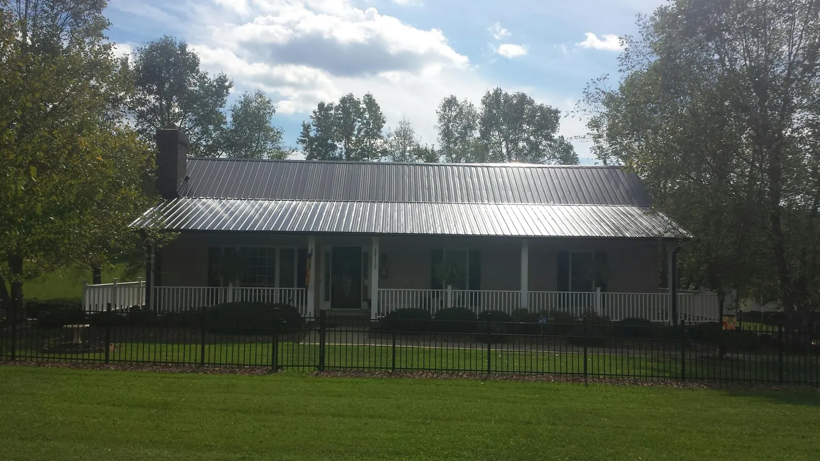 Gray metal roof on a brick ranch with a full width front porch — Gutter Guard Installation work by our crew in Ruthton