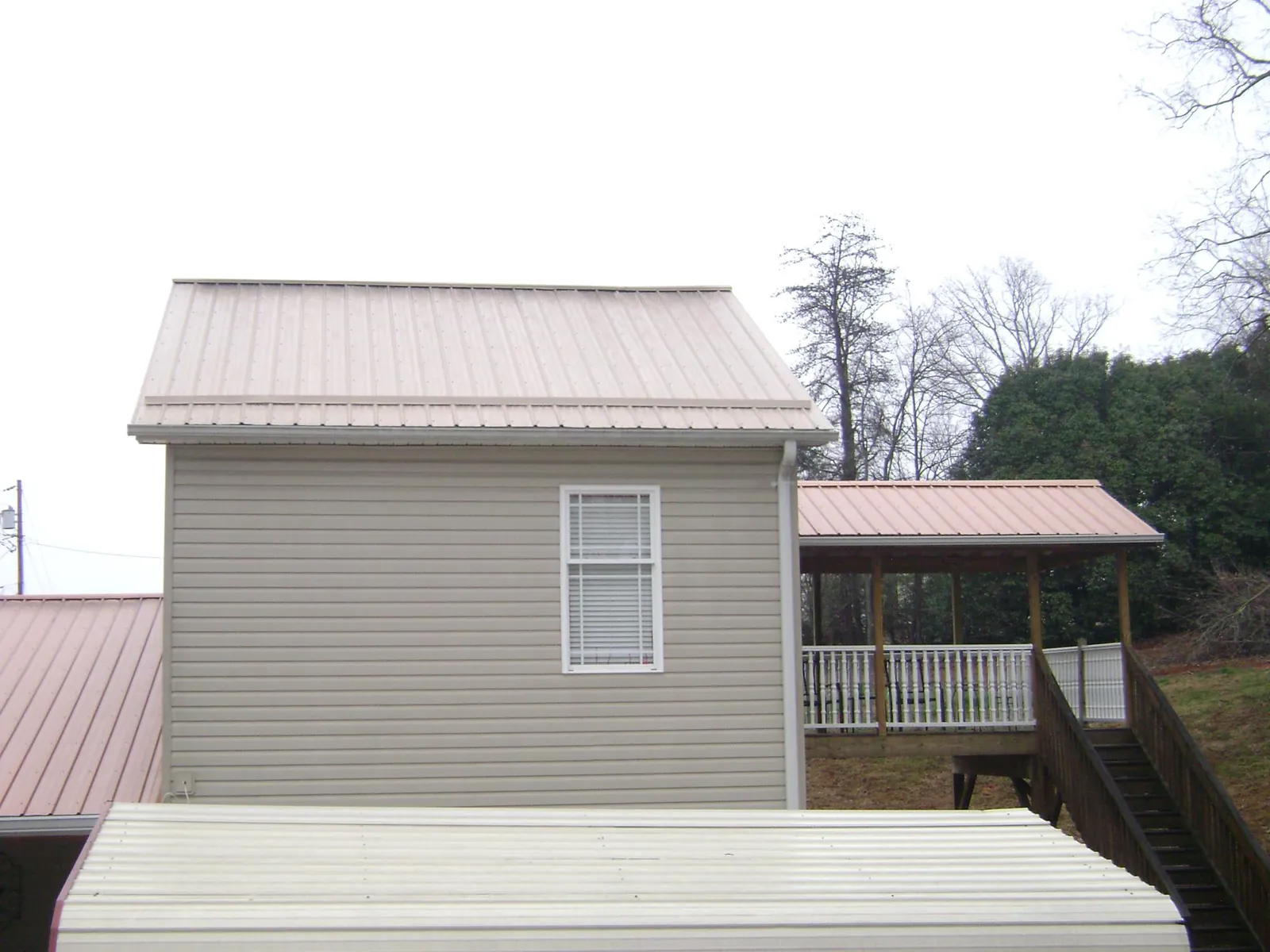 Tan metal roofs on a two story addition and attached porch, from a Roof Replacement job in Ruthton