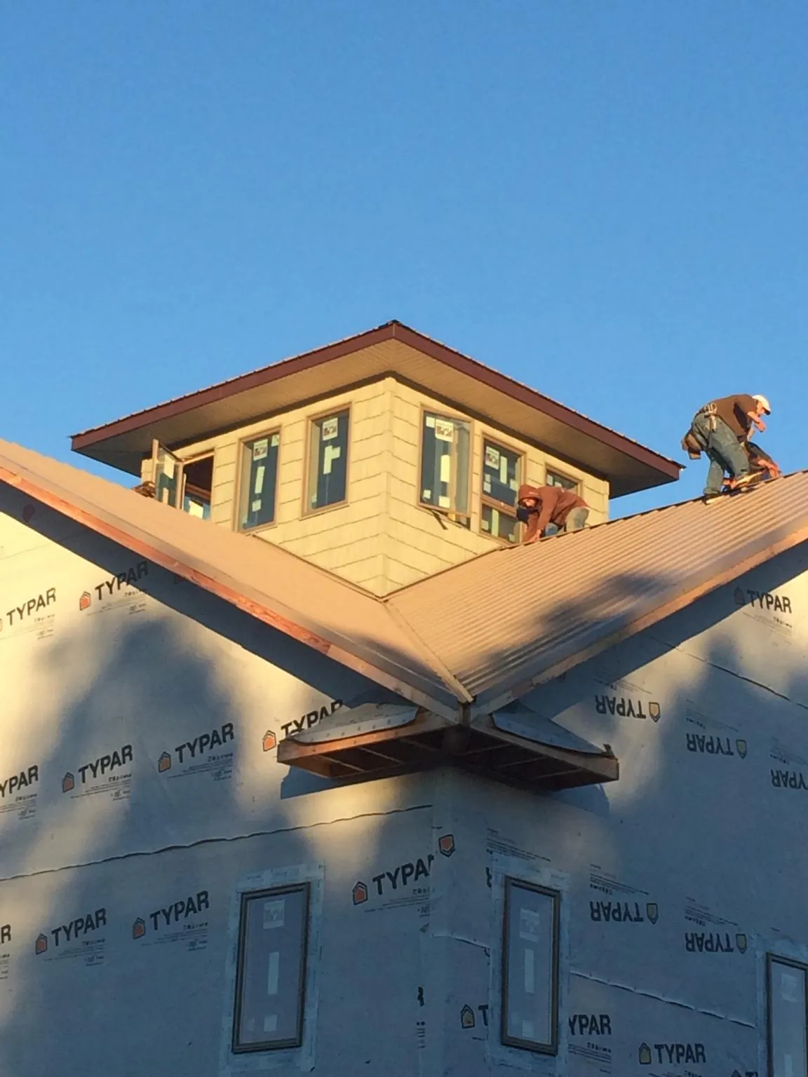 Roofers working around a rooftop cupola on a new metal roof at sunset — Roof Waterproofing in Ruthton by Roofing Brothers